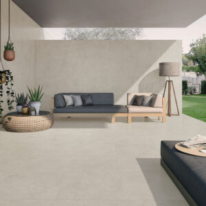 Terraza con pavimento cerámico beige, sofá modular, plantas y jardín