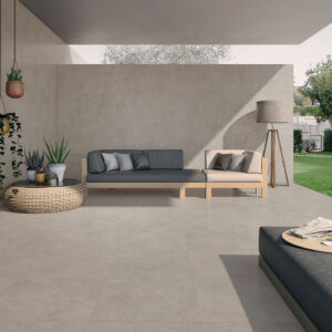 Terraza moderna con grandes baldosas cerámicas gris, sofá modular, plantas y césped