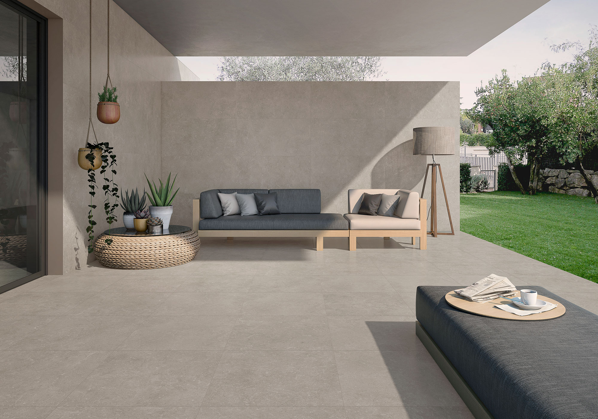 Terraza moderna con grandes baldosas cerámicas gris, sofá modular, plantas y césped