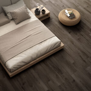 Suelo cerámico imitación madera oscuro con cama baja y puf de mimbre