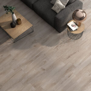 Suelo cerámico efecto madera roble claro en salón con sofá gris, mesa y lámpara