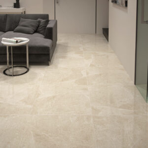 1092_ALAPLANA_chelsea-beige Pavimento cerámico beige efecto mármol en salón con sofá gris y mesas auxiliares