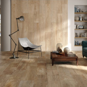 Sala luminosa con pavimento y revestimiento cerámico efecto madera, sofá y butaca