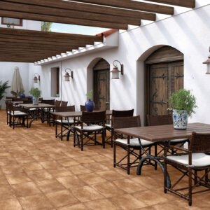 Terraza con pavimento cerámico terracota, mesas de madera y puertas rústicas