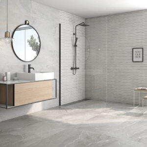 Baño moderno con pavimento y revestimiento cerámico gris, mueble flotante, espejo redondo y ducha.