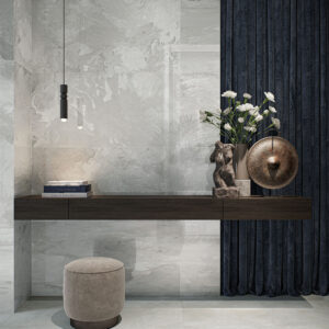 3696_ALAPLANA_URANO-GREY_HQ Exposición de azulejos grises efecto mármol en pared y suelo, con mueble y decoración