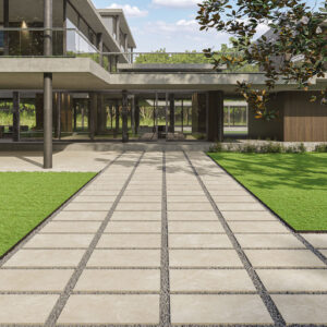 Pasarela de losas cerámicas con juntas de grava en exposición frente a fachada moderna.