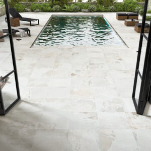 Terraza con piscina sobre pavimento cerámico blanco veteado y puertas plegables negras