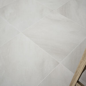 ALAPLANA ABERDEEN detalle RGB Suelo cerámico gris claro en baldosas cuadradas con juntas finas y pata de taburete de madera