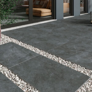 Terraza con grandes losas cerámicas gris oscuro y bandas de grava entre ellas.