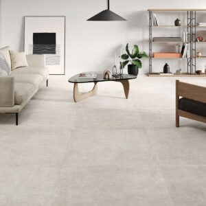 AMB-BONN-WHITE-100X100-MATE Salón minimalista con grandes azulejos cerámicos beige claro, sofá y mesa baja