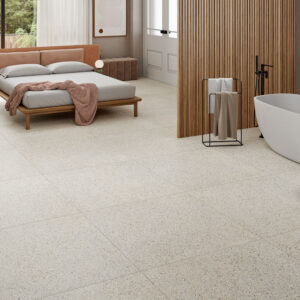 Showroom con dormitorio y bañera sobre suelo cerámico gran formato tipo terrazo beige