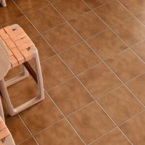 Suelo cerámico terracota, mesa de madera y taburetes con asiento trenzado y flores