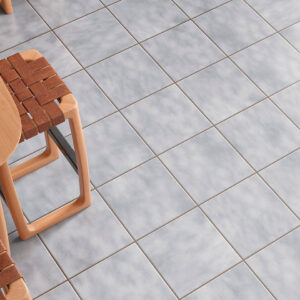 Pavimento cerámico gris efecto mármol junto a mesa de madera y taburetes trenzados