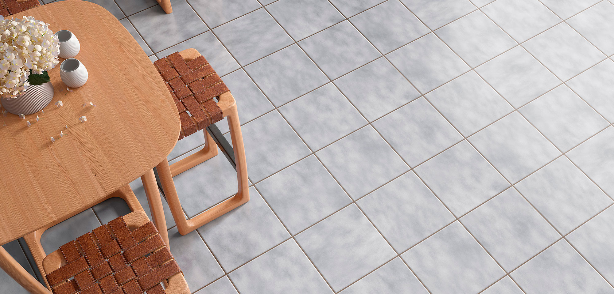 Pavimento cerámico gris efecto mármol junto a mesa de madera y taburetes trenzados