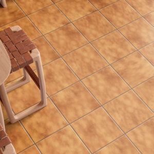 Suelo de baldosa cerámica color terracota con mesa de madera y taburetes trenzados