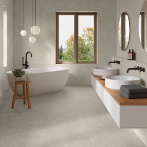 Baño expositivo con bañera exenta, doble lavabo y azulejos cerámicos beige en suelo y paredes