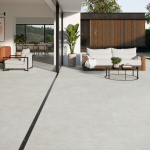 Zona interior-exterior con grandes losas cerámicas claras y muebles de salón.