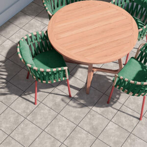 Pavimento cerámico gris en baldosas cuadradas junto a mesa redonda de madera y sillas verdes