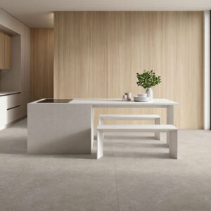 Tienda de azulejos con pavimento cerámico gris, isla blanca, paneles de madera y ventanal