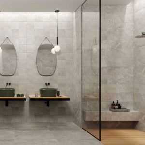 Exposición baño: azulejos grises, doble lavabo sobre encimera y mampara de ducha