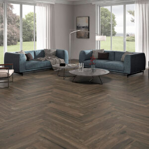 Pavimento cerámico efecto madera en espiga en salón con sofás azul petróleo y ventanales