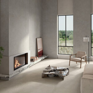 AMB_STN_KRETA-GREY-120X280_PEARL-120X120-(2) Showroom con pavimento y revestimiento cerámico gris, chimenea, sofá y grandes ventanales