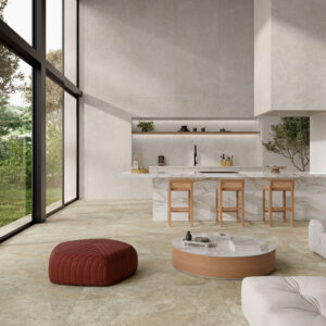 AMB_STN_KRETA-PEARL-120X280_NATURAL-120X120_DRAC-120X280 Tienda con pavimento cerámico beige, isla de mármol, grandes ventanales y mobiliario neutro