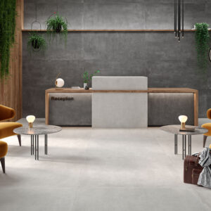CASTLETON-ANTRACITA-75X150_GRIS-120X120 Recepción con pavimento y revestimiento cerámico gris, butacas mostaza, mostrador de madera