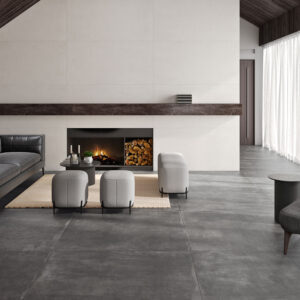 CASTLETON-BLANCO-75X150_ANTRACITA-120X120 Salón expositor con grandes losas cerámicas grises, chimenea y mobiliario.