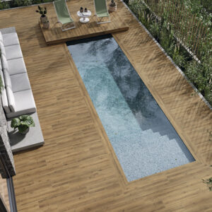 Piscina rectangular con pavimento cerámico efecto madera, sofá exterior y tumbonas