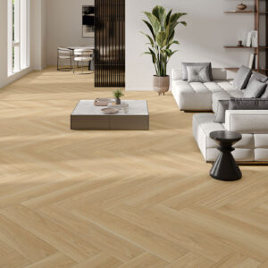 NUK-ROBLE-23X120 Sala de exposición con pavimento cerámico en espiga madera clara, sofá modular y mesas.