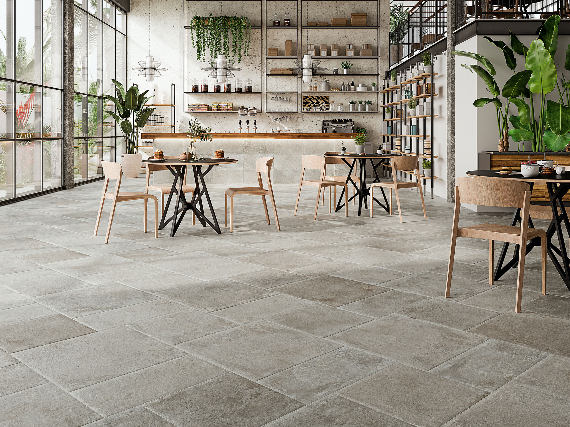 SAINT-ANDREWS-GREY-MULTIFORMATO-(1) Tienda azulejos con pavimento cerámico gris, mesas y sillas madera junto a grandes ventanales