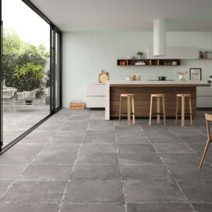 Cocina moderna con isla de madera y pavimento cerámico gris hacia el patio