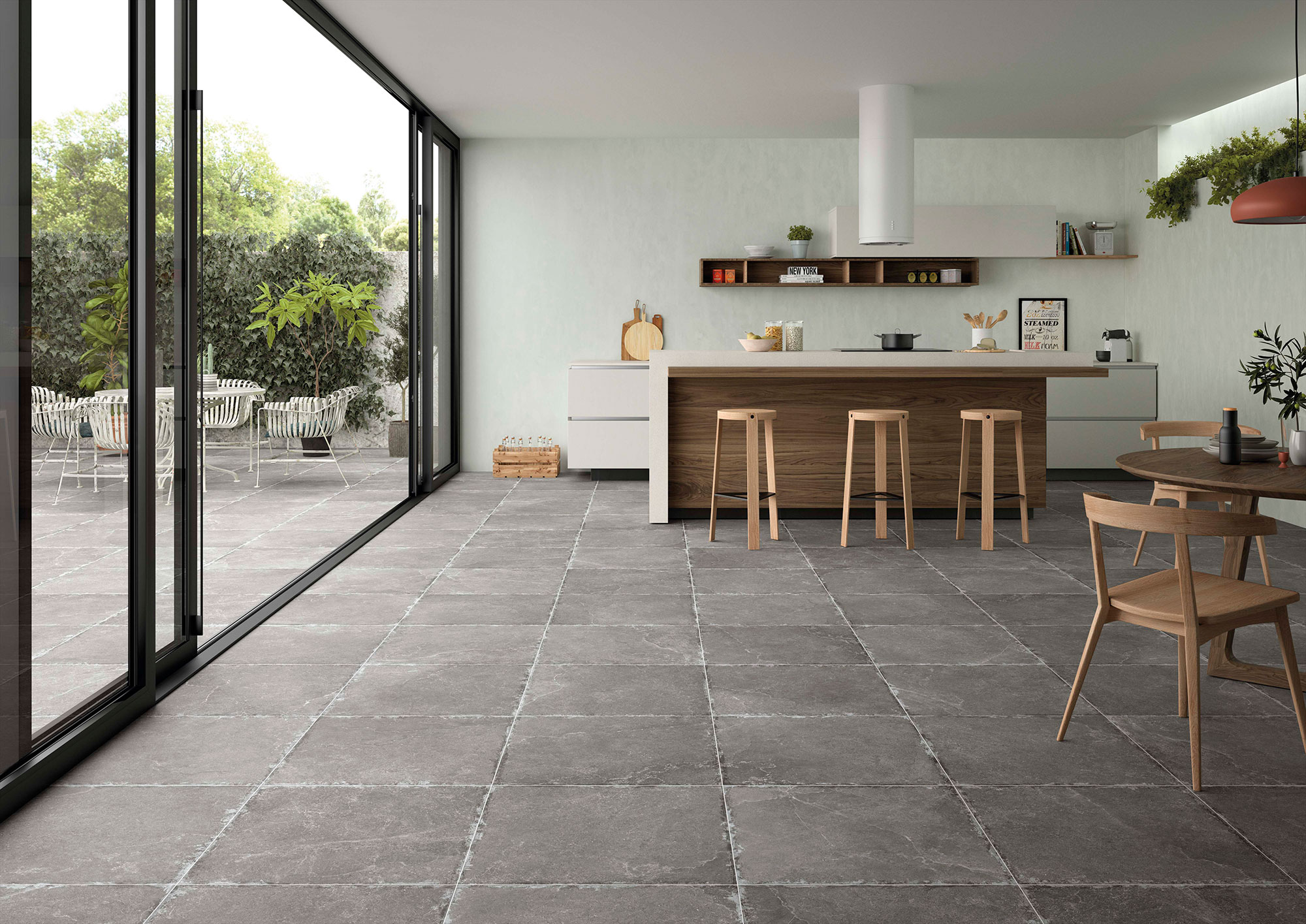 Cocina moderna con isla de madera y pavimento cerámico gris hacia el patio