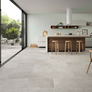 Cocina moderna con isla y amplios suelos cerámicos grises y terraza ajardinada