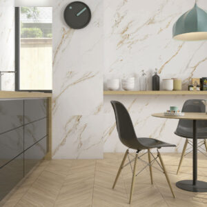 Cocina con azulejos efecto mármol, pavimento en espiga madera y muebles modernos.