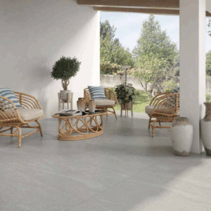 Porche con pavimento cerámico gris, sillones y mesa de ratán y jarrones decorativos