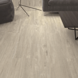 Pavimento cerámico efecto madera en salón con sofá, mesa baja y pufs