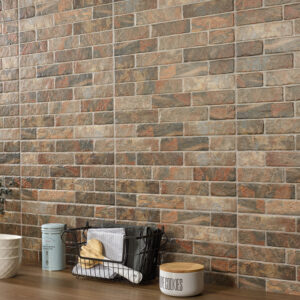 Pared de azulejos cerámicos efecto ladrillo en tonos tierra junto a encimera con utensilios.